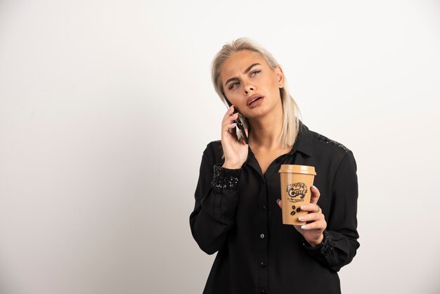 Woman speaking on mobile phone and holding a cup of coffee . High quality photo