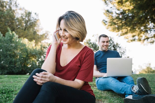 Woman speaking on phone near man with laptop