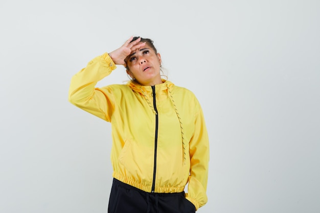 Woman in sport suit looking far away with hand over head , front view.