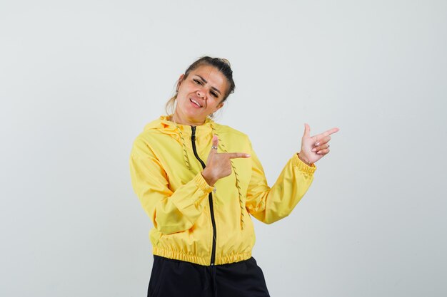 Woman in sport suit pointing to the side and looking confident , front view.