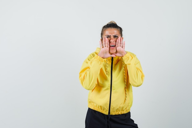 Woman in sport suit shouting or telling secret and looking excited , front view.