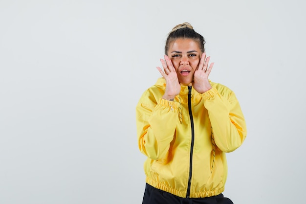 Woman in sport suit telling secret with hands near mouth , front view.