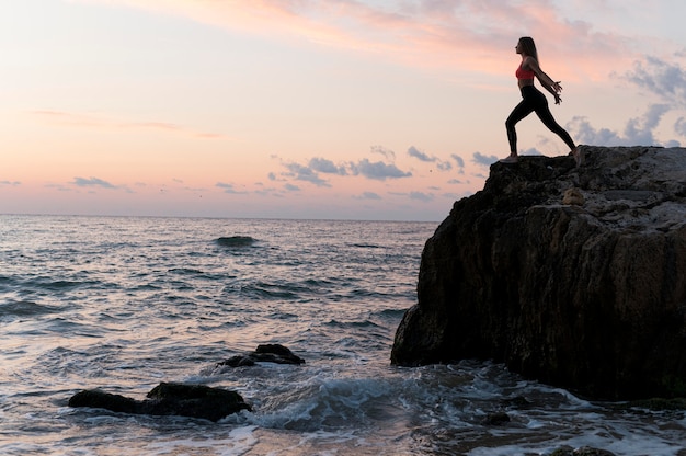 Woman in sportswear standing on a coast with copy space