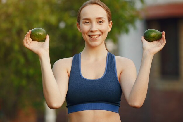 Sportwearの女性は果物を保持します