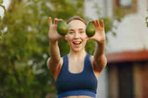 Free photo woman in a sportwear holds a fruits