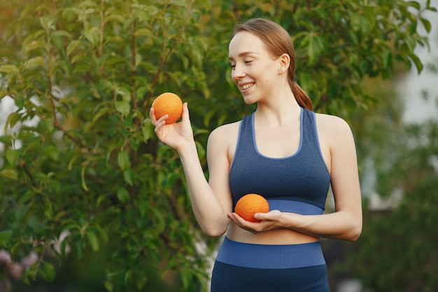 Женщина в спортивной одежде держит фрукты