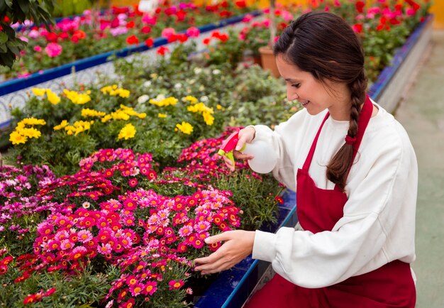 Woman spraying flowers in greenhouse