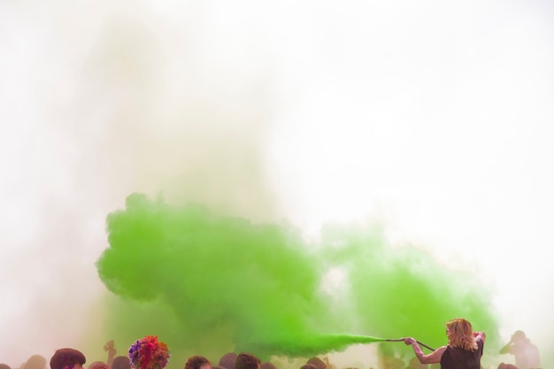 Woman spraying the green holi color with pipe over the crowd