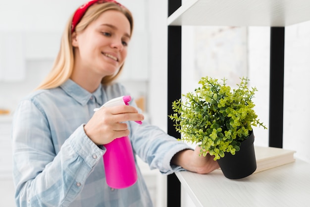 Woman spraying plant at home