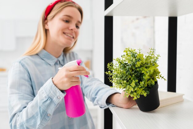 woman spraying plant at home