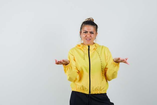 Woman spreading palms aside in sport suit and looking puzzled. front view.