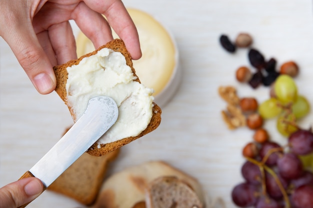 Woman spreading soft cheese on toasted bread