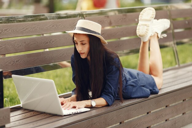 봄 도시에있는 여자. 노트북과 레이디. 벤치에 앉아 소녀입니다.