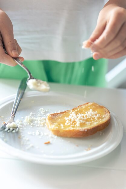 パンに粉チーズをふりかける女性