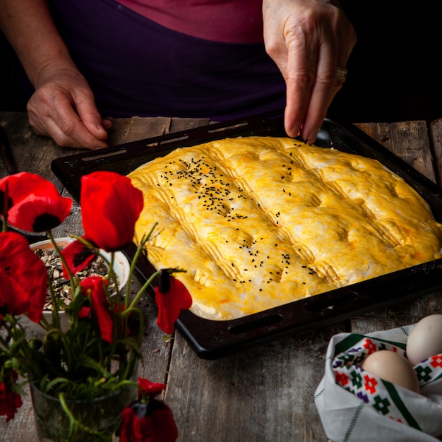 Donna che spruzza la spezia su pasta prima di cuocere la vista dell'angolo alto.