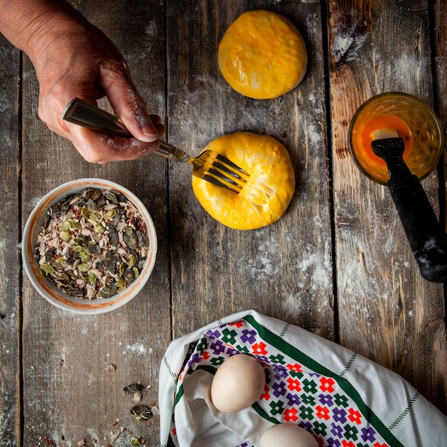 Woman squashing dough with fork before baking top view.