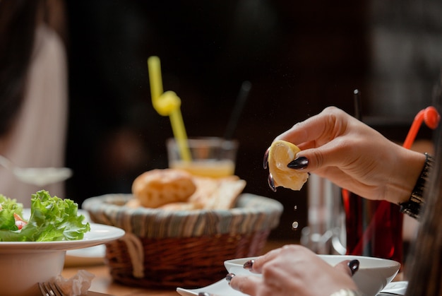 woman squeeze lemon to her soup at lunch table