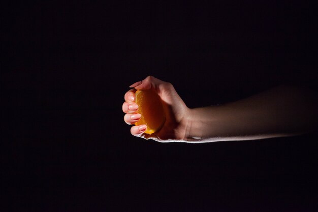Женщина сжимает сок из апельсина