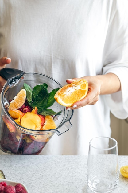 Free photo a woman squeezes orange juice into a blender making a fruit smoothie