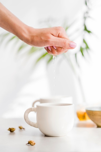 Woman squeezing lemon over cup