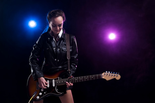 Женщина на сцене с огнями играет на гитаре