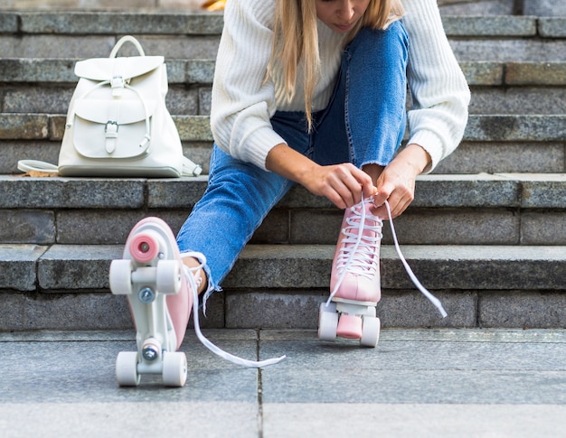 Woman on stairs tying shoelaces on roller skates