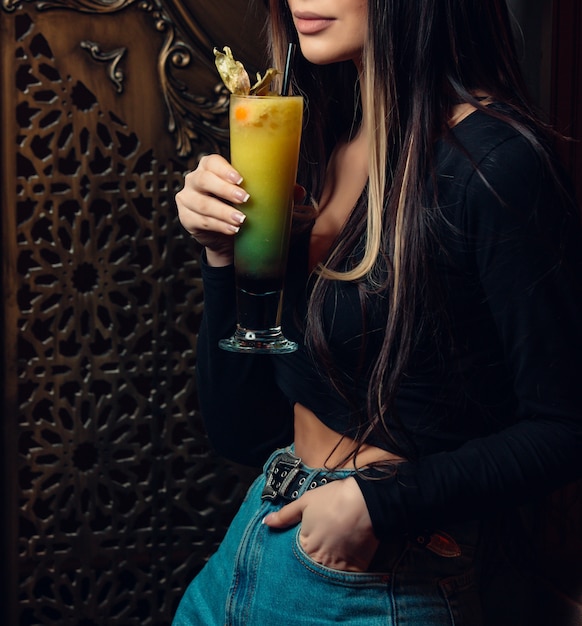 Бесплатное фото Женщина стоит и держит красочный коктейль в баре