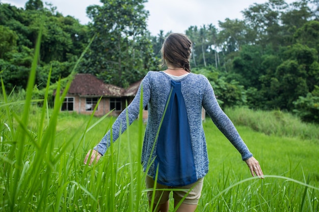 Woman standing back and open arms in tropical forest