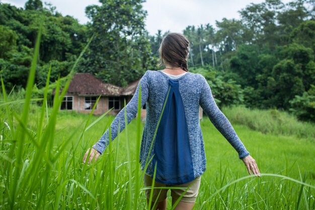 Woman standing back and open arms in tropical forest