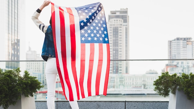 Woman standing on balcony with big American flag