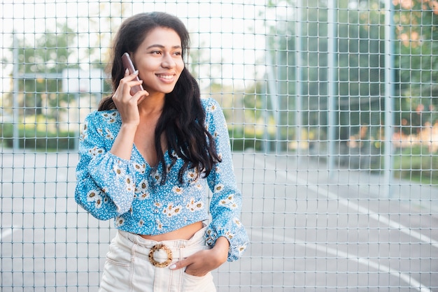 Woman standing next to a basketball field talking at the phone