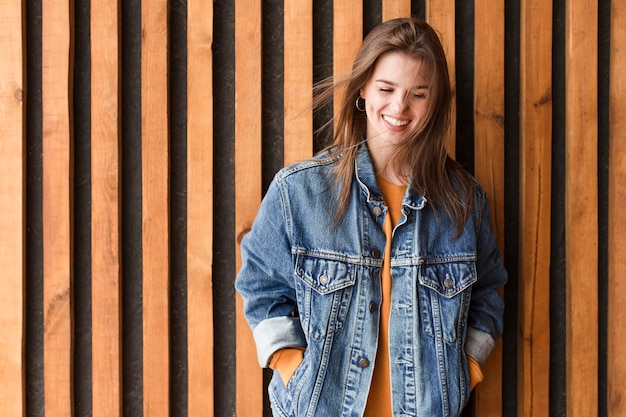 Foto gratuita donna che sta accanto alla parete di legno