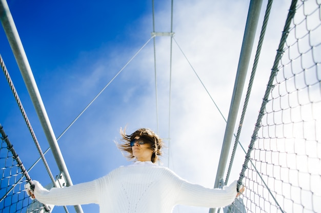 Woman standing on bridge high in sky