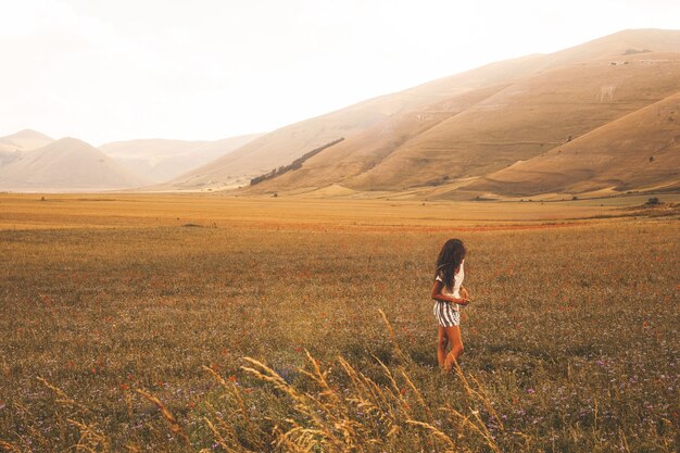 Woman standing on brown grass field