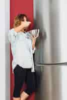 Free photo woman standing and eating near fridge