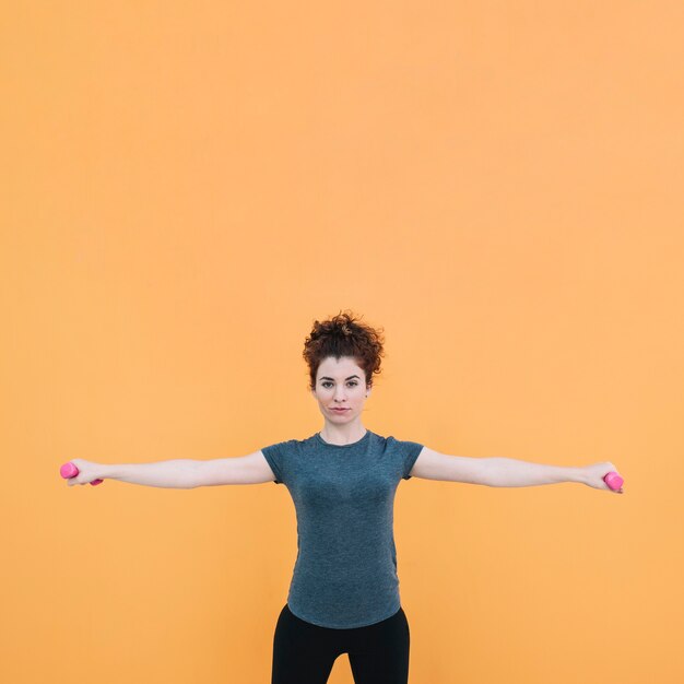 Woman standing and exercising with dumbbells