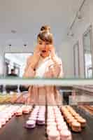 Free photo woman standing in front of the glass showcase with pastries