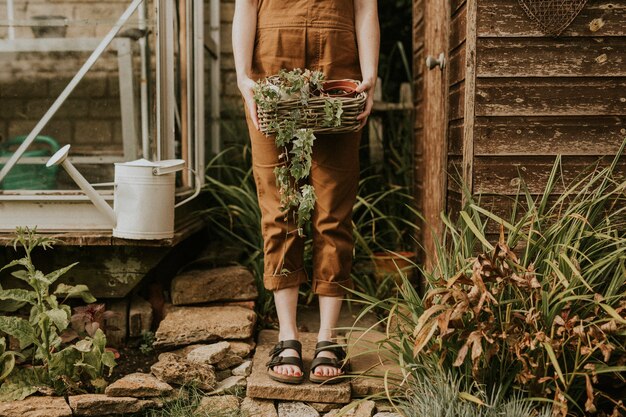 관엽 식물과 함께 창고 앞에 서있는 여자