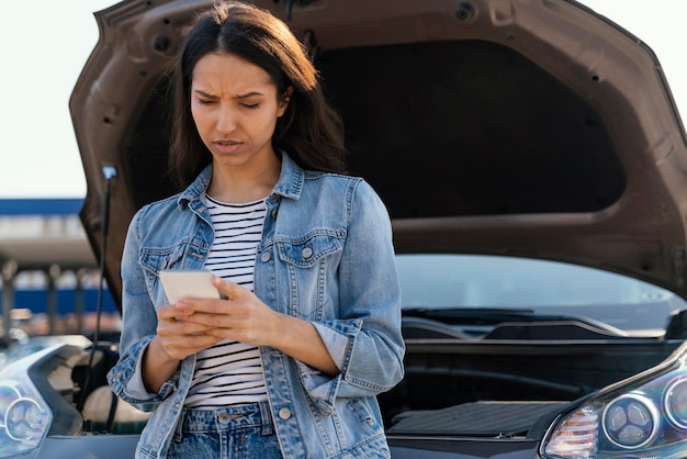 Free photo woman standing next to her broken car