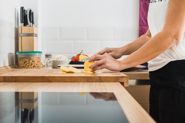 Woman standing at kitchen cutting potatoes