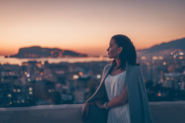 woman standing looking at sunset and looking thoughtful