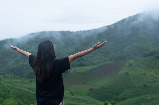 A woman standing in the middle of the mountain with a refreshing pose