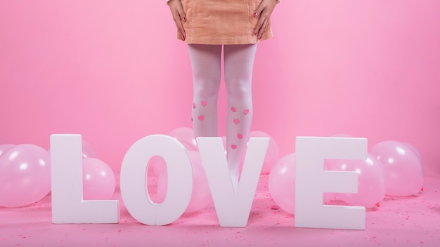 Woman standing near Love inscription and balloons 