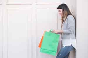 Free photo woman standing near wall with shopping bags