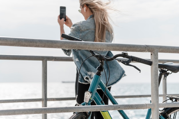 무료 사진 그녀의 자전거 옆에 서서 사진을 찍는 여자