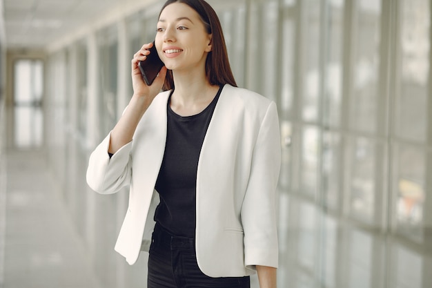 Женщина стоит в офисе с телефоном