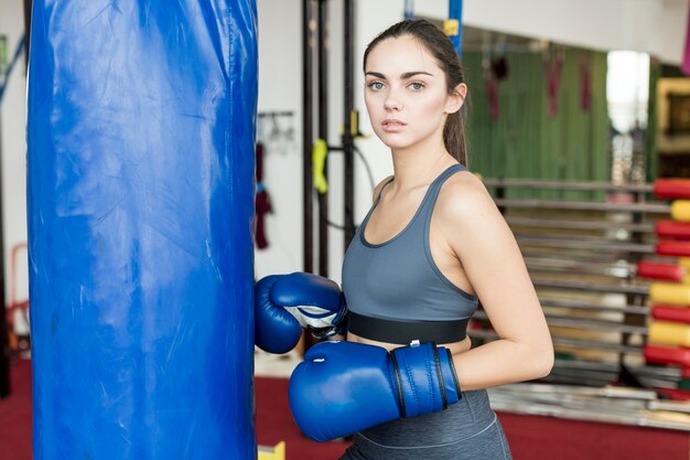 Woman standing at punch bag in gym