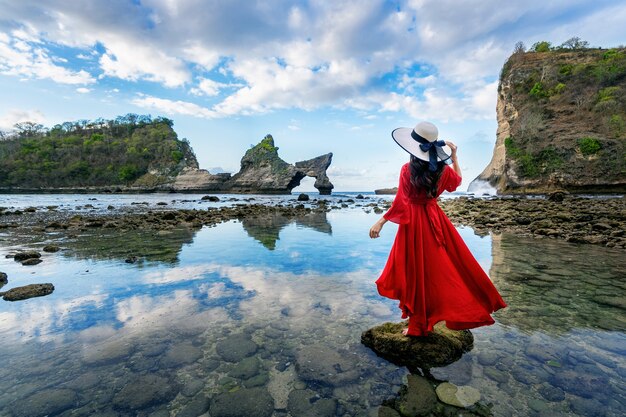 발리, 인도네시아의 누사 페니 다 섬 Atuh 해변에서 바위에 서있는 여자