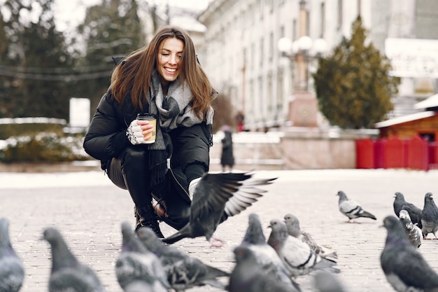 Woman standing on the street surrounded by pigeons