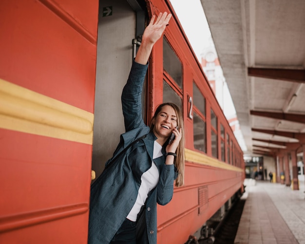 Free photo woman standing in the train entrance and waving